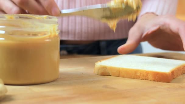 Женщина готовит сэндвич с арахисовым маслом — стоковое видео