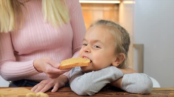 Madre alimentando sandwich de niña con mantequilla de maní — Vídeos de Stock