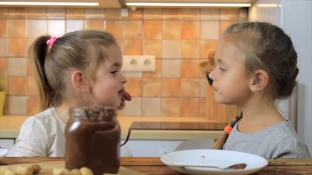İki küçük kız birlikte gülüyor ve çikolatalı kremayla oynuyorlar. — Stok video