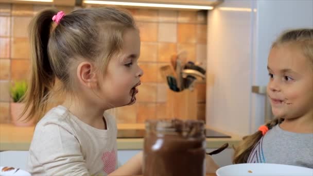 Duas meninas rindo e brincando com creme de chocolate juntas — Vídeo de Stock