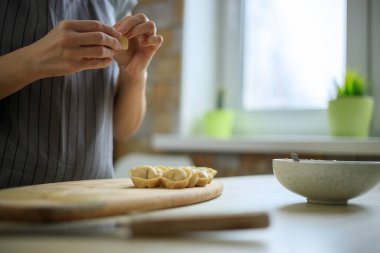 Geleneksel ravioli hazırlayan kadın, hamura et koyuyor.