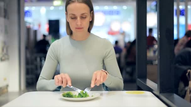 Mujer comiendo brócoli en la cafetería — Vídeo de stock