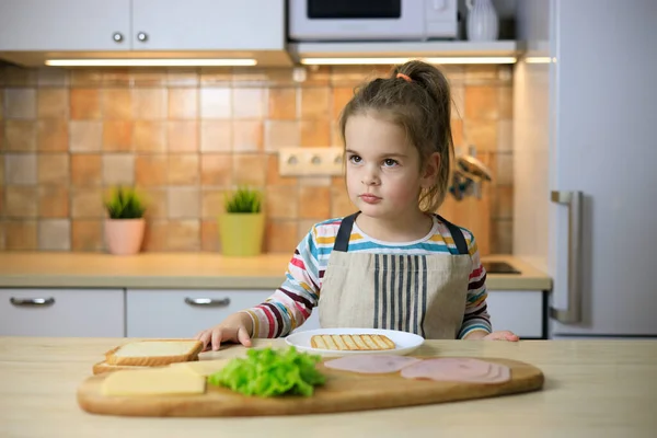 Küçük kız salata ve peynirli sandviç yapıyor. - Stok İmaj