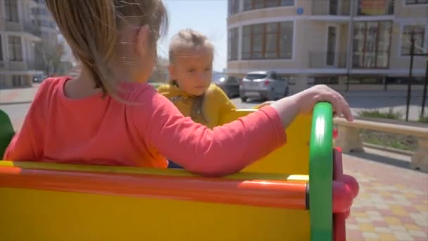 Zwei kleine Geschwister schaukeln und lachen auf Spielplatz — Stockvideo