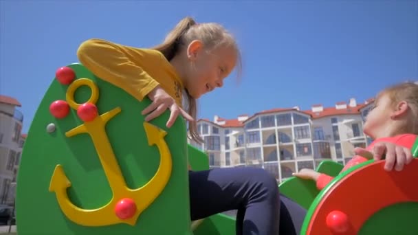 Zwei kleine Geschwister schaukeln und lachen auf Spielplatz — Stockvideo