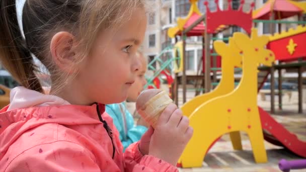 Dwie małe dziewczynki jedzące lody na placu zabaw — Wideo stockowe