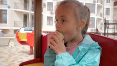 Küçük kız oyun alanında dondurma yiyor.