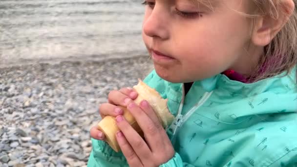 Dziewczynka je lody na plaży. — Wideo stockowe