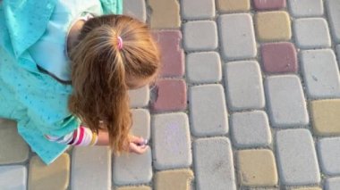 İki küçük kız kardeş kaldırıma boya kalemleri çiziyor.