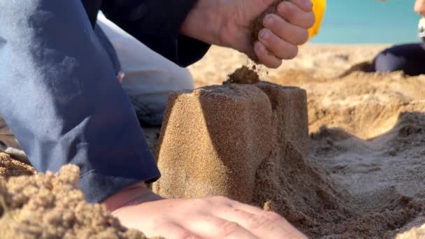 Küçük çocuk kumsalda kumdan kale inşa ediyor. — Stok video