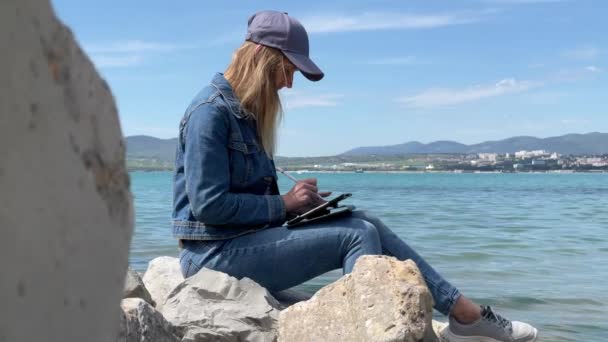 Mujer dibujo en la tableta cerca de la costa del mar — Vídeos de Stock