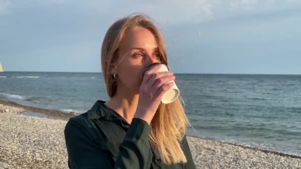 Jeune femme marchant près de la mer et buvant du café — Video