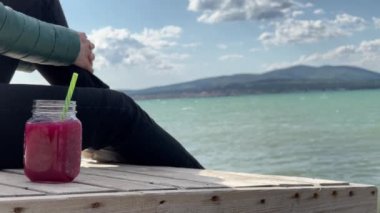 Deniz kıyısındaki kavanozda smoothie içen kadın.