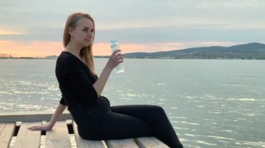 Deniz kıyısındaki şişeden su içen kadın