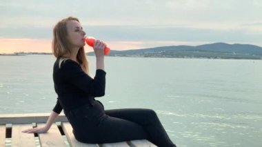 Deniz kıyısında meyve suyu içen bir kadın.