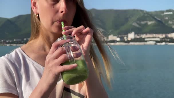Žena pije zelený detox smoothie na pláži — Stock video