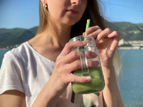 在海滩上喝绿色脱氧核糖核酸的女人 — 图库照片