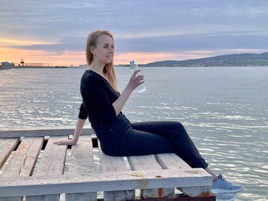 Deniz kıyısındaki şişeden su içen kadın