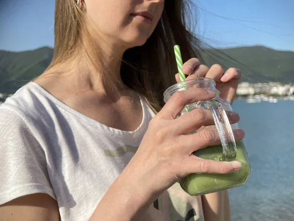 Kobieta pije zielony detox smoothie na plaży — Zdjęcie stockowe