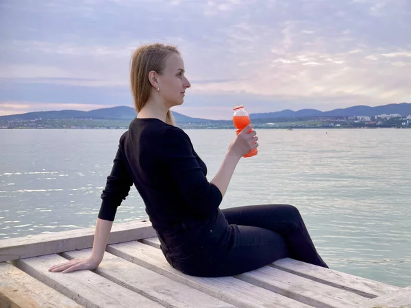 Mulher bebendo smoothie fruta de garrafa na costa do mar — Fotografia de Stock