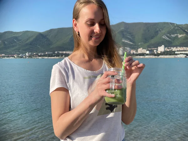 Mulher bebendo smoothie desintoxicação verde na praia — Fotografia de Stock