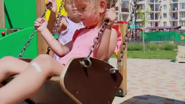 Kleines Mädchen hilft ihrer kleinen Schwester beim Reiten auf Schaukel — Stockvideo