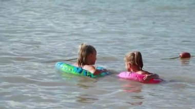 İki küçük kız kardeş denizde birlikte yüzüyor.