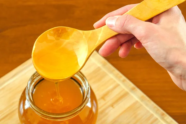 Рука держит деревянную ложку с медом — стоковое фото