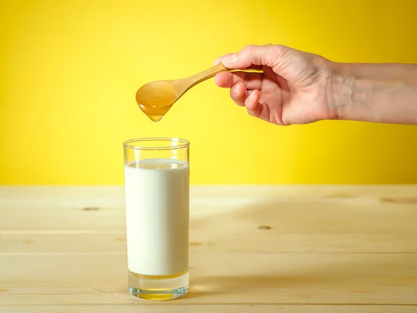 Мед падает с ложки в стакан молока — стоковое фото