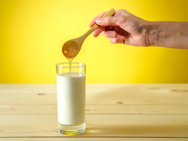 Honing vallen van lepel in een glas melk — Stockfoto