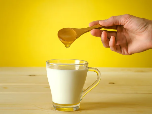 Honing vallen van lepel in een glas melk — Stockfoto