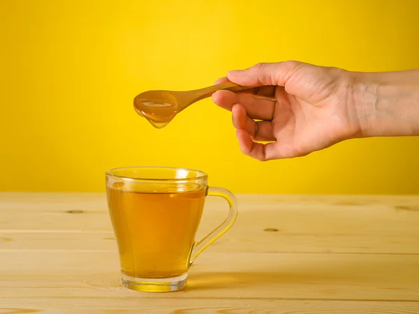 Мед падает с ложки в стакан чая с лимоном — стоковое фото
