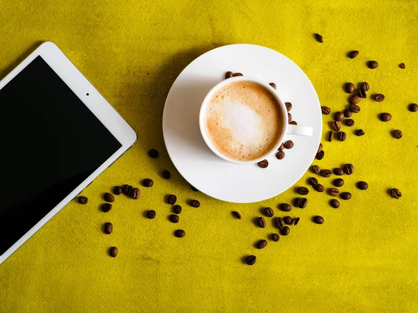 Šálek kávy s tabletem na zeleném pozadí — Stock fotografie