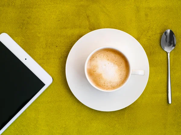 Tasse Kaffee mit Tablette auf grünem Hintergrund — Stockfoto