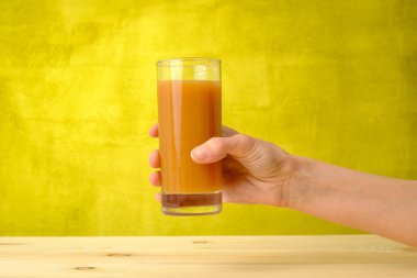 Kadın eli şeftali suyu bardakta tutuyor