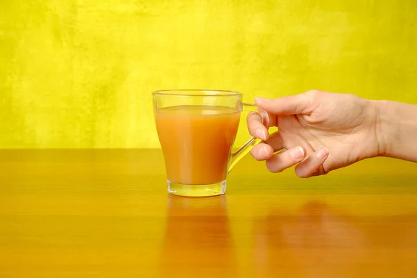 Woman's hand is holding peach juice in the glass — Stock Photo, Image