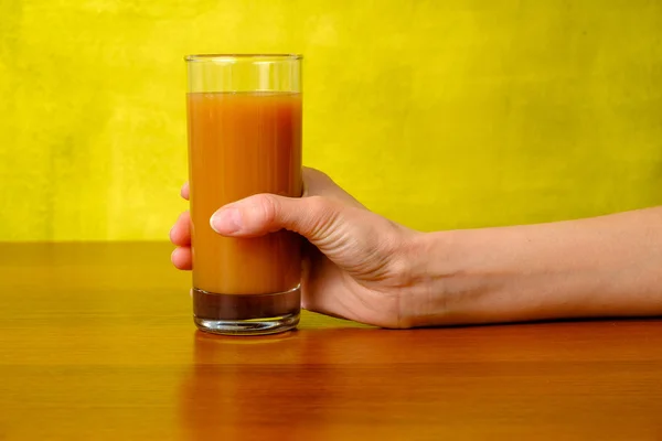 Woman's hand is holding peach juice in the glass — Stock Photo, Image