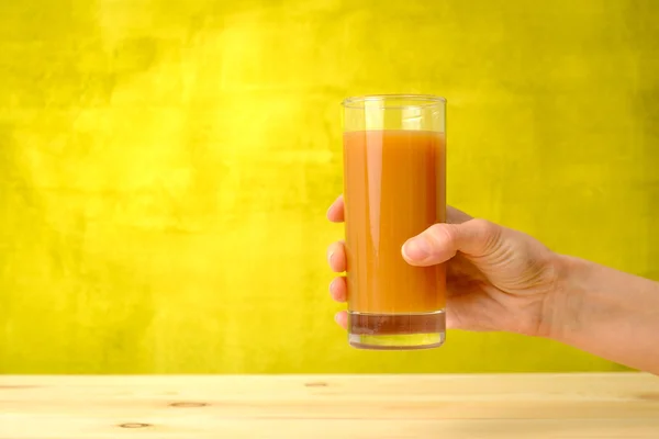 La main de la femme tient du jus de pêche dans le verre — Photo