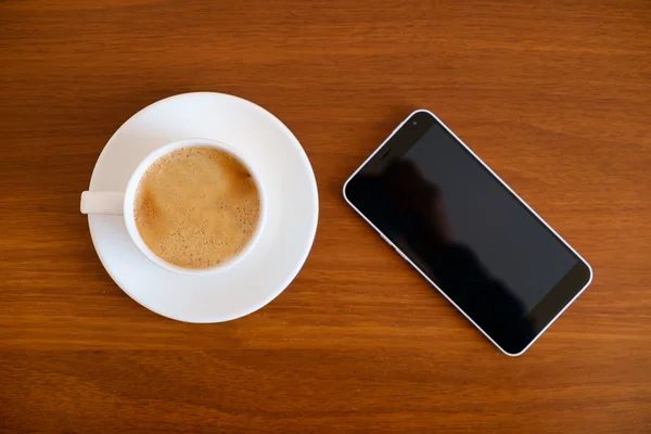 Smartphone com xícara de café expresso na mesa de madeira — Fotografia de Stock