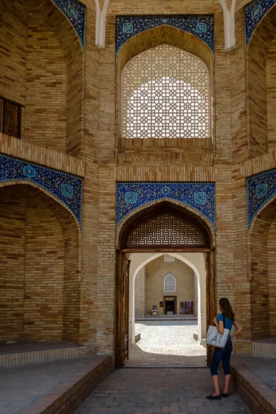 Woman is looking in the open door in old Islamic complex in Tashkent