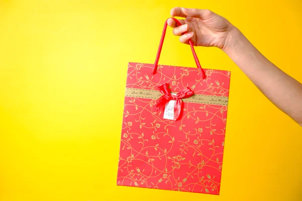 Weibliche Hand mit roter Tasche auf gelbem Hintergrund — Stockfoto