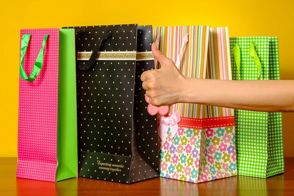 Mujer mostrando pulgares hacia arriba. Concepto de éxito, bolsas de compras en el fondo . — Foto de Stock