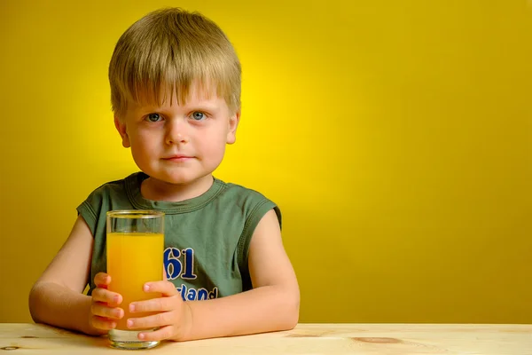 Glücklicher kleiner Junge mit einem Glas Orangensaft. — Stockfoto