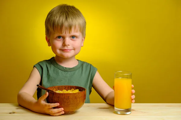 Niño guapo con hojuelas de maíz en plato de madera —  Fotos de Stock