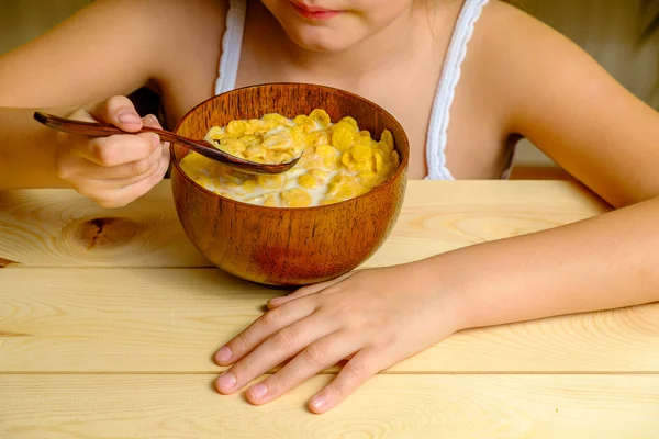 Nettes Mädchen mit Cornflakes auf Holzteller — Stockfoto