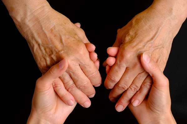 Hands of young woman holding hands of an elderly woman — Stock Photo, Image