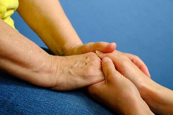 Hands of young woman holding hands of an elderly woman — Stock Photo, Image