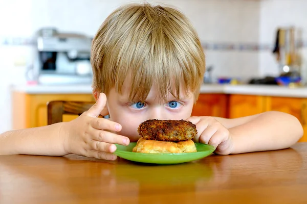 Kleiner Junge mit Schnitzel in der Küche — Stockfoto