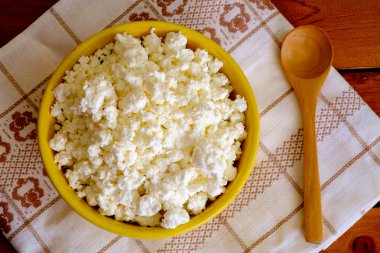 Sarı seramik kase ve tahta kaşık süzme peynir