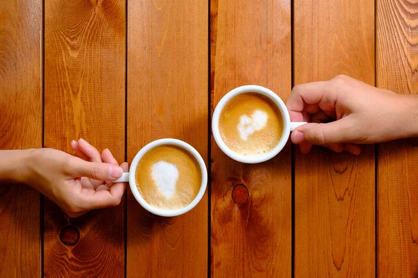 Homem e mulher segurando uma xícara de café no café — Fotografia de Stock